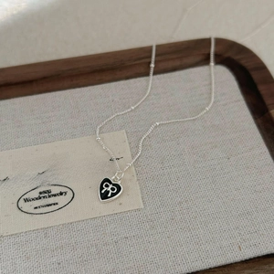925 silver necklace with black heart pendant and white bow detail on textured tray
