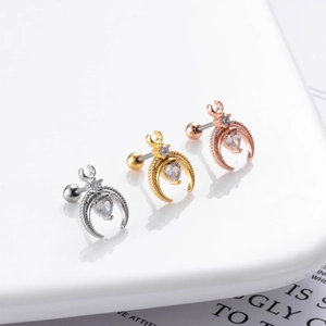 Macro detail of dragonfly moon cartilage studs in silver, gold, and rose gold finishes