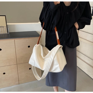 Detail of white large Boston bag featuring contrast brown straps and soft glossy leather