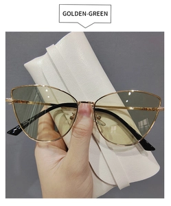 Close-up of golden metal cat-eye sunglasses with green lenses held by hand