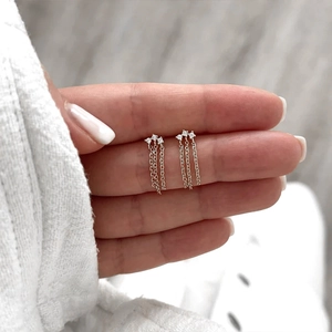Macro shot of silver tassel earrings featuring three sparkling zircon stones on hands