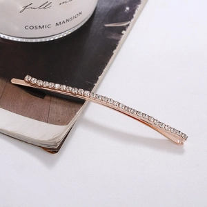 Rose gold bobby pin with shimmering rhinestones on a minimalist white background