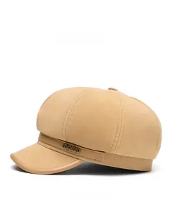 Seitenansicht der beige Schiebermütze mit strukturiertem Stoff und Vintage-Metallemblem
