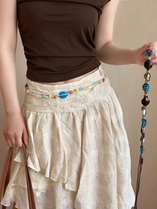 Détail d'une chaîne de taille faite main avec perles en résine bleue et coquillages blancs