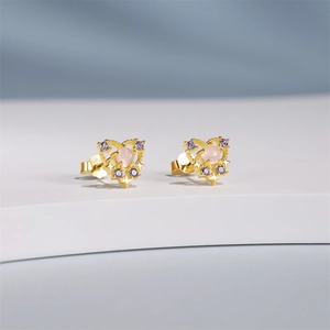 Detailed close-up of golden heart studs with pink center stone and purple accents