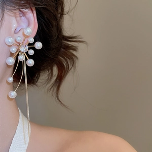 Close-up of flower pearl earrings with long metallic tassel and zircon details