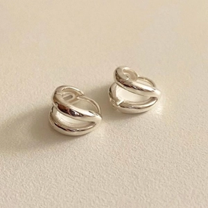 Close-up of dual-layer intertwined 925 sterling silver hoop earrings with high polish