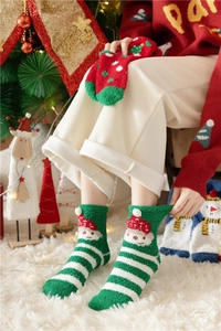 Close-up of green and white striped coral fleece Christmas socks with festive patterns