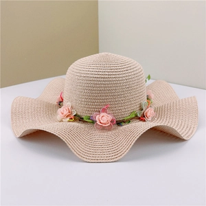Detail of summer straw hat with wavy brim and delicate pink floral rose wreath decoration