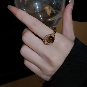 Elegant gold ring with brown gemstone worn by model next to a wine glass detail