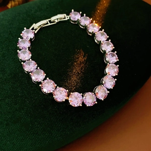 Detail of round cut pink zircon bracelet on green velvet background with metal clasp