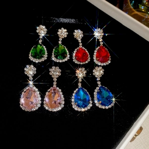 Macro detail of pear-cut gemstone earrings in green, red, pink, and blue crystal colors
