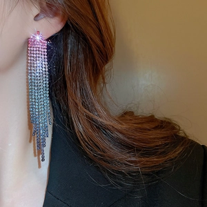 Close-up of dangling tassel earrings featuring gradient pink to blue rhinestones