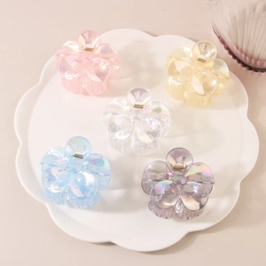 Close-up of five pearlescent flower hair claws in pink, yellow, blue, and purple tones