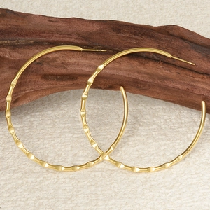 Detail of large gold 304 stainless steel hoop earrings with textured hammered finish