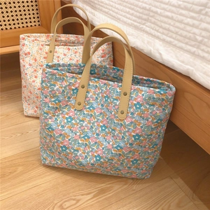 Detail of floral tote bags with reinforced synthetic leather handles and metal rivets