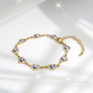 Macro detail of gold heart link bracelet featuring blue evil eye beads and lobster clasp