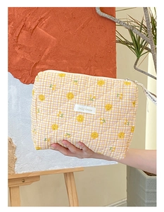Détail d'une trousse à maquillage matelassée jaune avec sourires et fermeture éclair