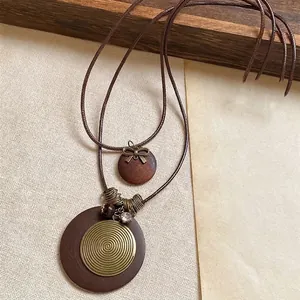 Close-up of ethnic necklace with wooden discs and spiral bronze metal charms on brown cord