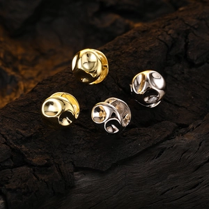 Irregular glossy silver and gold hoop earrings set on dark textured wood background