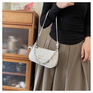 Detail of white embossed leather handbag featuring silver metal logo and chain strap