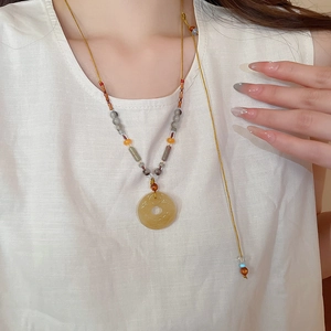 Collier ethnique en perles d'agate grise avec pendentif donut jaune porté par un mannequin
