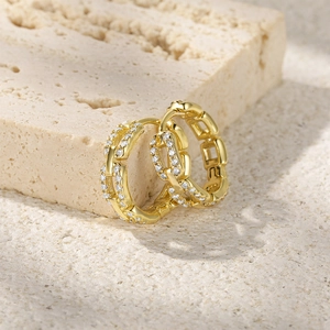 Close-up of golden wavy hoop earring with paved zircon stones on stone base