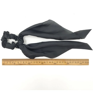 Detail view of black satin scrunchie with long ribbons and size reference scale