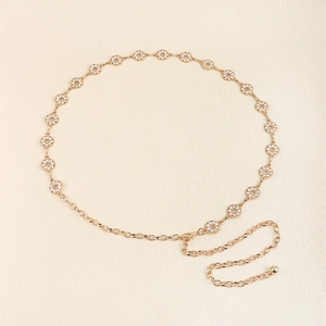 Detailed view of adjustable gold rhinestone waist chain with lobster clasp on beige background
