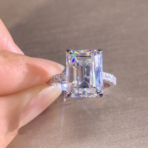 Silver ring with emerald cut square gemstone and pavé stones in a handheld macro view