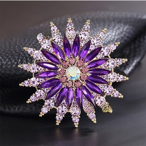 Macro shot of purple sunflower brooch with sparkling crystals on black leather background