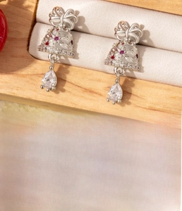 Detail of silver drop bell earrings with red zircon bows on a wooden jewelry display
