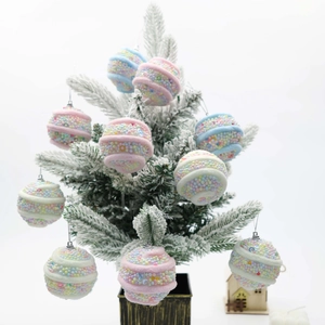 Pink and blue Christmas tree ball ornaments with glitter and beads on snow-dusted tree