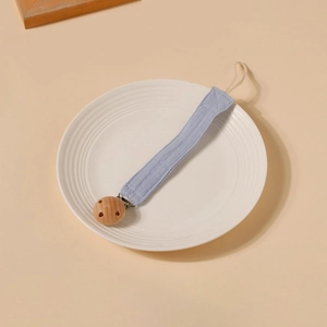Détail de l'attache-tétine pour bébé avec sangle en coton bleu clair et clip rond en hêtre