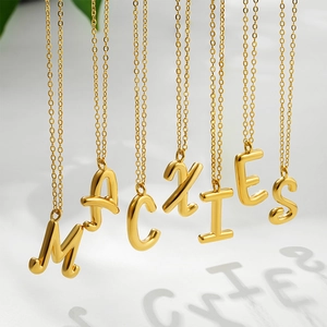 Minimalist 18K gold plated stainless steel letter necklaces on white marble