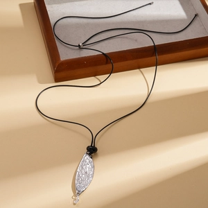 Macro detail of leaf-shaped silver pendant with embossed texture on black leather cord