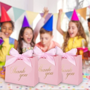 Détail de trois boîtes cadeaux de mariage roses avec texte doré Thank You et rubans fins