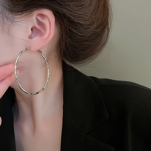 Detailed view of large silver hoop earrings with spiral texture on professional model