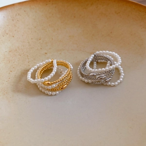 Detail of layered gold-plated pearl rings displayed in a minimalist ceramic dish