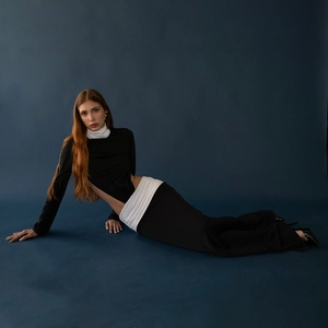 Detail of waist cutout design and white pleated patchwork on a black slim dress