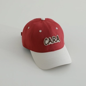 Detail of retro red cotton baseball cap with embroidered CARA letter patch and cream brim