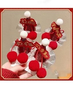 Detail of red New Year hair clips with white pompoms and festive embroidery patches
