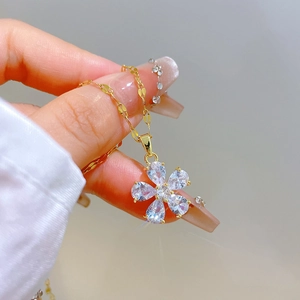 Close-up of a gold flower pendant with sparkling crystals on a unique flat link chain