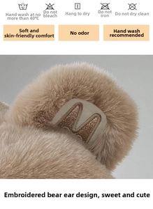 Detail of plush bear hat showing the golden letter M embroidery and soft fleece texture