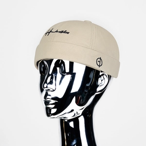 Bonnet docker beige avec broderie noire sur mannequin argenté, style urbain chic