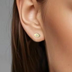 Golden evil eye stud earring with white zircon on ear, chic minimalist jewelry style