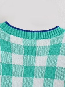 Detail view of green and white checkerboard knit sweater with blue contrasting neckline