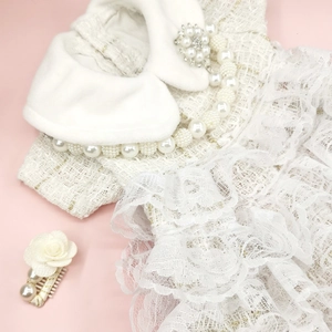 Detail of tweed pet dress with pearl collar and lace hem on pink background