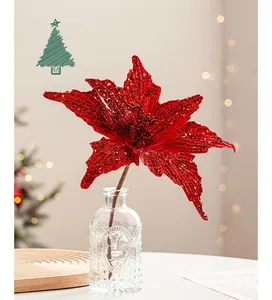 Close-up of red glitter artificial poinsettia flower in glass vase with festive bokeh