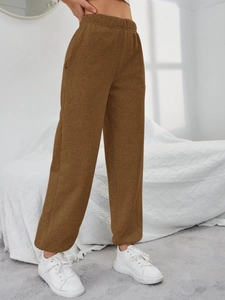 Dettaglio dei pantaloni marroni a vita alta con elastico in vita e morbido tessuto a maglia